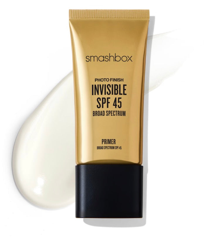 A squeeze tube of Smashbox Invisible SPF 45 Primer with a metallic gold body and black cap, shown on a white background with a white cream smear behind it.